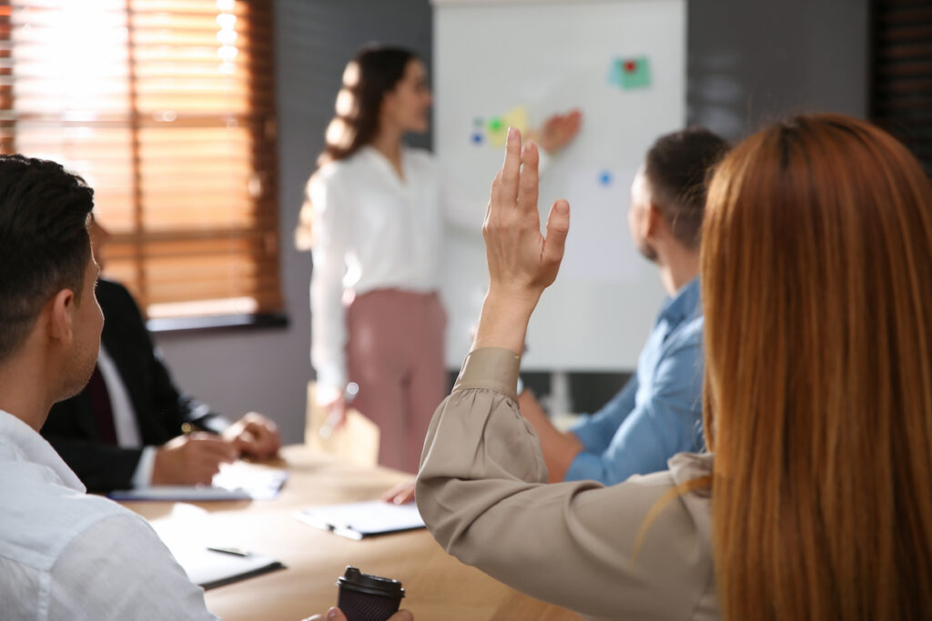 A young professional raising a hand during a team meeting.